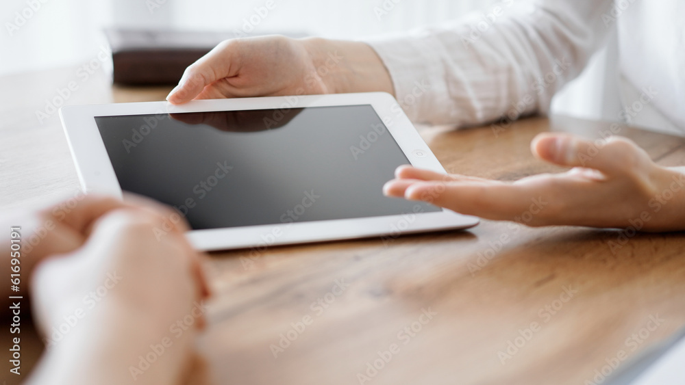 Fototapeta premium Contract papers are lying at the wooden desk while business people discussing something at the wooden desk at the background. Teamwork, partnership, contract signing concept