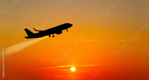 The plane takes off at sunset.