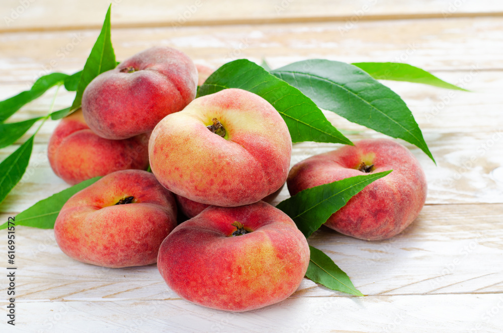 Fresh Flat Peaches, Chinese Saturn Donut Peaches with Leaves on Wooden Bright Background Fresh Flat Peaches, Chinese Saturn Donut Peaches with Leaves on Wooden Bright Background