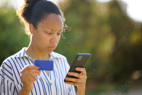 фотографія Worried black online buyer checking phone