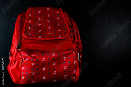 Tela A red colored school bag with stars and scribes designed on it shot against blackboard in the background -Kindergarten concept