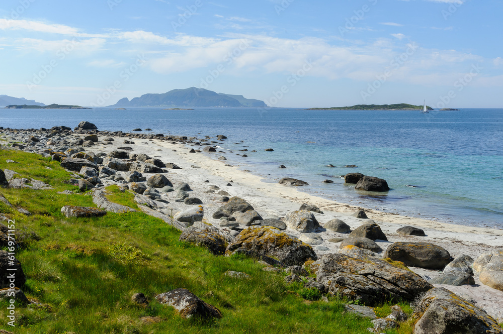 beach with rocks and grass on the coast with islands in the distance beach with rocks and grass on the coast with islands in the distance