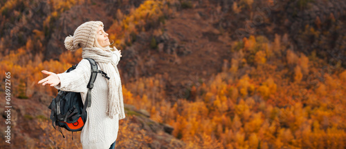 Tourist Woman with Backpack stands with her arms outstretched and enjoys the Autumn mountains