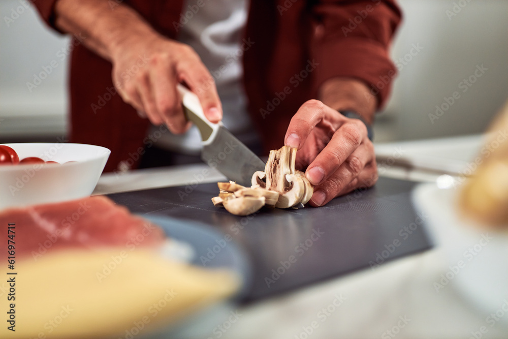 A man cutting mushrooms on a kitchen counter and preparing a delicious meal.