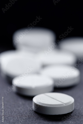 Medicine and drug concept. Macro shot of white tablets bunch on black background.