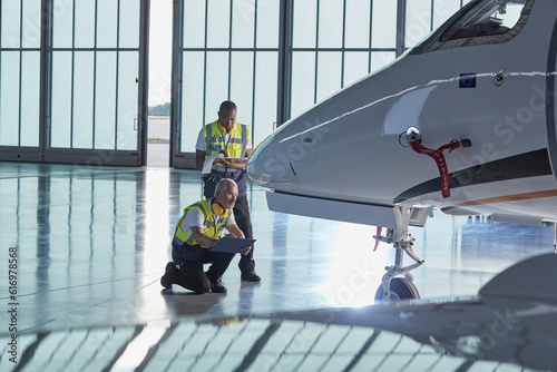 Bild auf Leinwand Air traffic control ground crew workers examining corporate jet in airplane hang