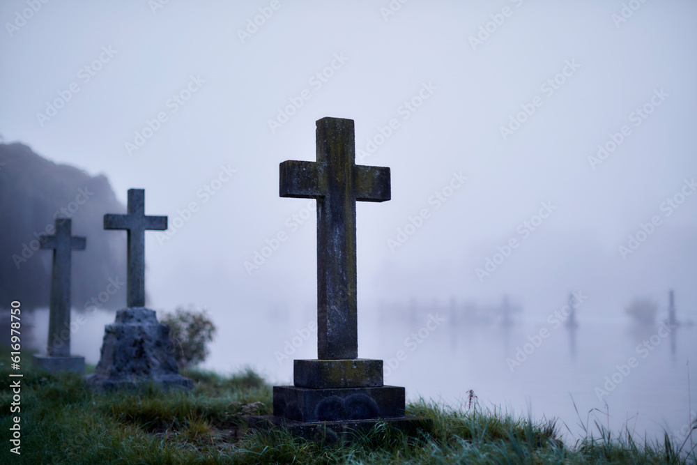 Crosses on gravestones in ethereal flooded foggy cemetery