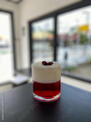 Strawberry syrup with milk foam with roselle tea as garnish on the black table at the coffeshop