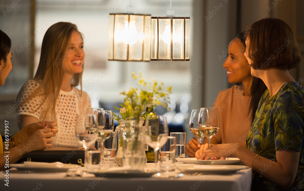 Smiling women friends dining and drinking wine at restaurant table Smiling women friends dining and drinking wine at restaurant table