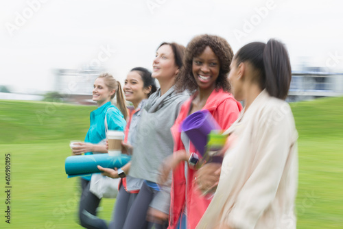 Smiling women friends walking with yoga mats and coffee