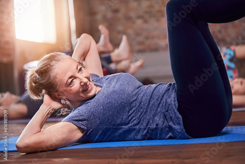 Mature woman doing sit-ups in exercise class gym studio