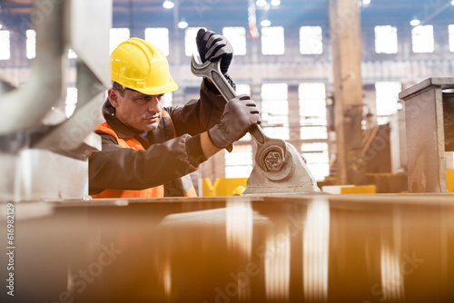 Steel worker using large wrench in factory photo