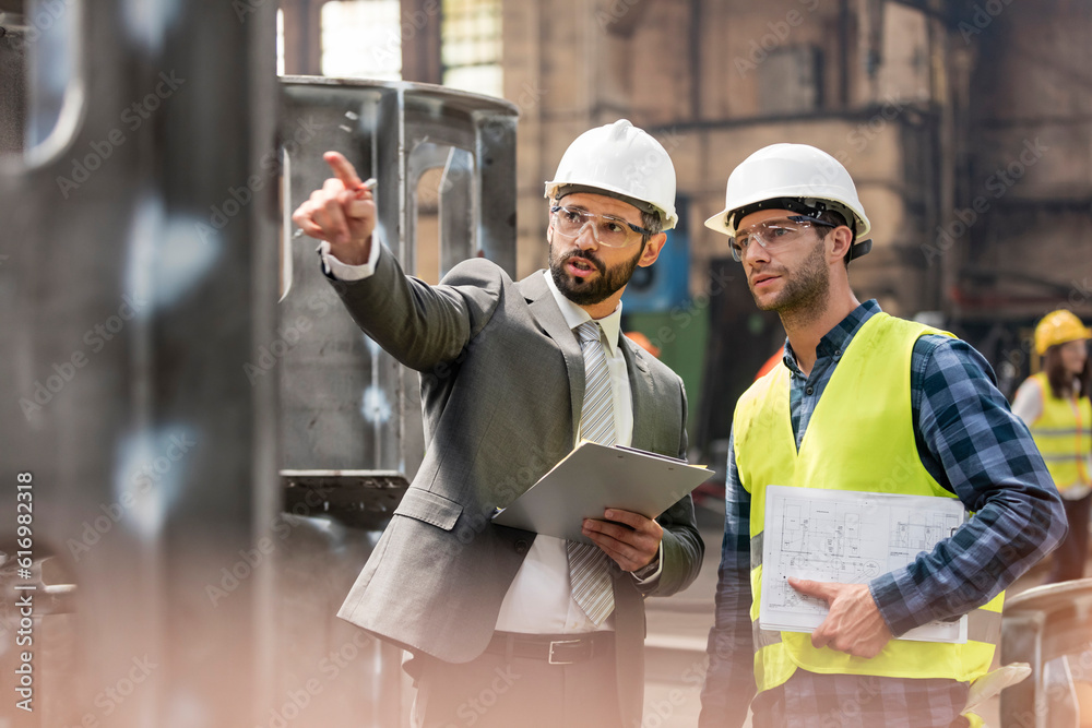 © KOTO - Manager and steel worker talking and looking away in factory