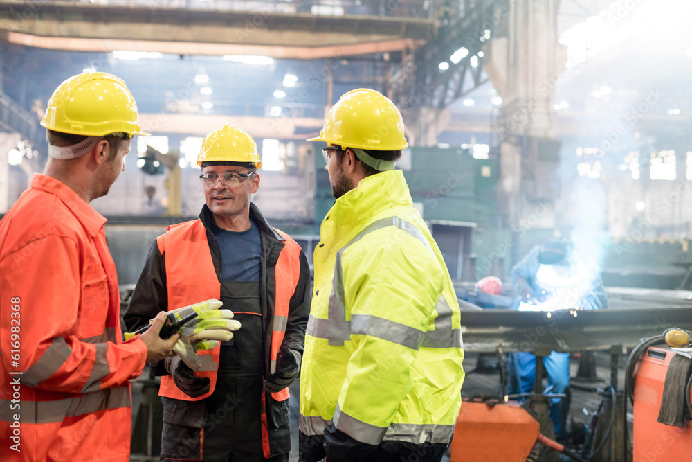 Steel workers talking in factory Steel workers talking in factory