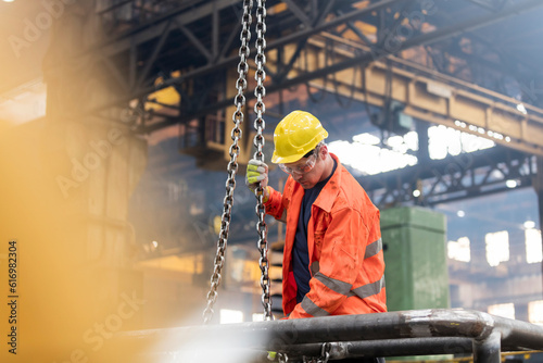 Steel worker fastening chain in factory