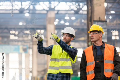 Schilderij op canvas Steel workers talking and pointing in factory