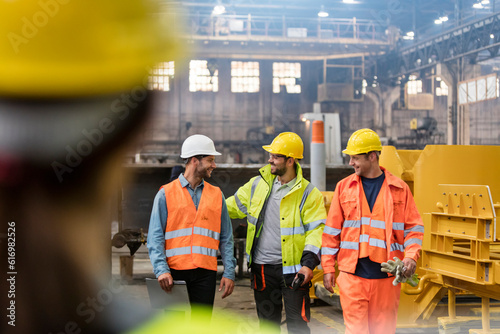 Steel workers walking and talking in factory