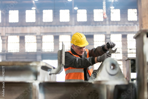 Steel worker using large wrench in factory photo
