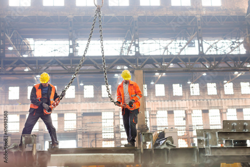 Steel workers with crane hooks in factory