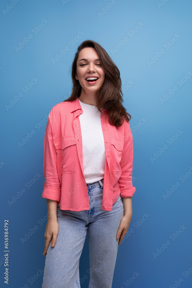 smiling positive brunette woman with dark hair below her shoulders posing on a studio background