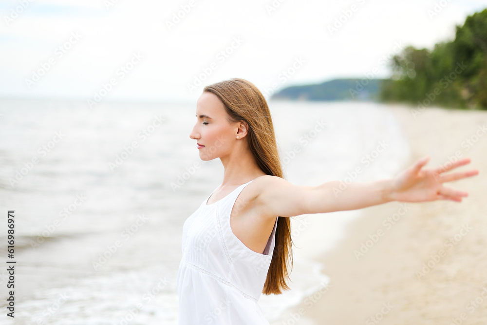 Happy smiling woman in free happiness bliss on ocean beach standing with open hands. Portrait of a multicultural female model in white summer dress enjoying nature during travel holidays vacation Happy smiling woman in free happiness bliss on ocean beach standing with open hands. Portrait of a multicultural female model in white summer dress enjoying nature during travel holidays vacation