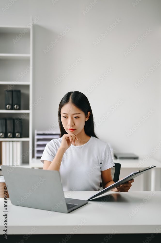 Successful Asian Businesswoman Analyzing Finance on Tablet and Laptop at Office Desk tax, report, accounting, statistics, and analytical research concept. Successful Asian Businesswoman Analyzing Finance on Tablet and Laptop at Office Desk tax, report, accounting, statistics, and analytical research concept.