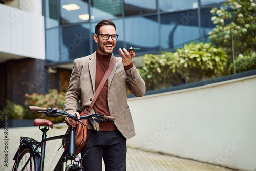 A businessman with a briefcase and bicycle talking on a speakerphone.