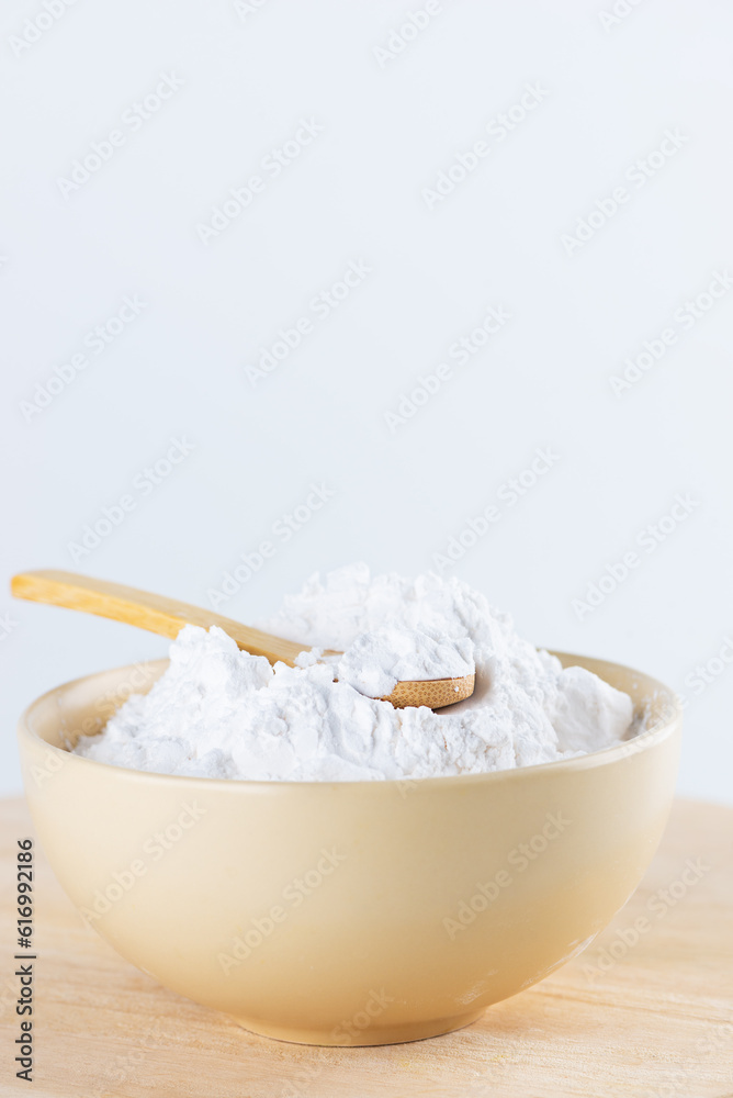 Tapioca starch in a spoon and bowl on a wooden board.