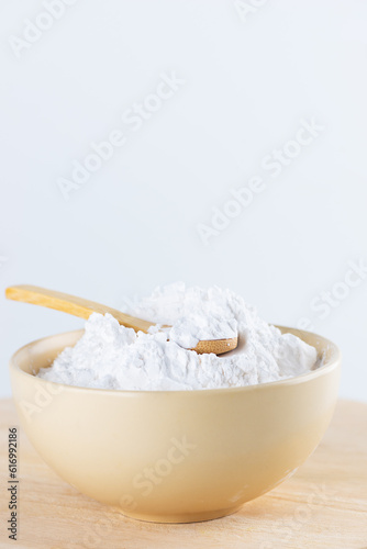 Tapioca starch in a spoon and bowl on a wooden board.