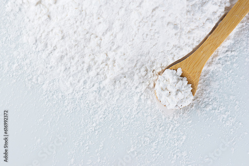 Heap tapioca starch and a wooden spoon, top view, copy space.