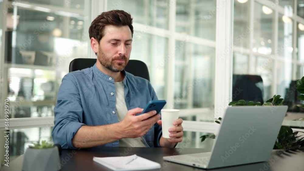 Businessman reading mobile app notification with coffee in office. Handsome office worker man typing with phone and thinking of ideas for social networking, online connection and internet. Businessman reading mobile app notification with coffee in office. Handsome office worker man typing with phone and thinking of ideas for social networking, online connection and internet.