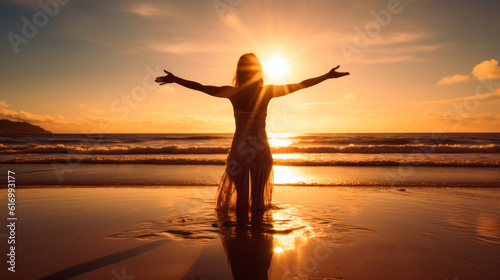 Woman on the beach worshiping the Sun at sunset with dramatic light