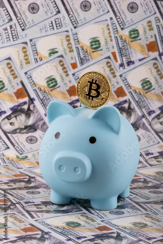 Gold coin with Bitcoin cryptocurrency symbol and piggy bank on the background of 100 American dollars banknotes