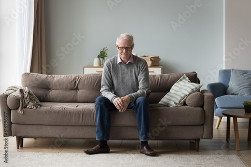 Upset thoughtful retired single man sit on couch alone, feels abandoned, suffer from weakness, having ageing disorders, grieving about past, missing for grown up children, looks deep in sad thoughts © fizkes