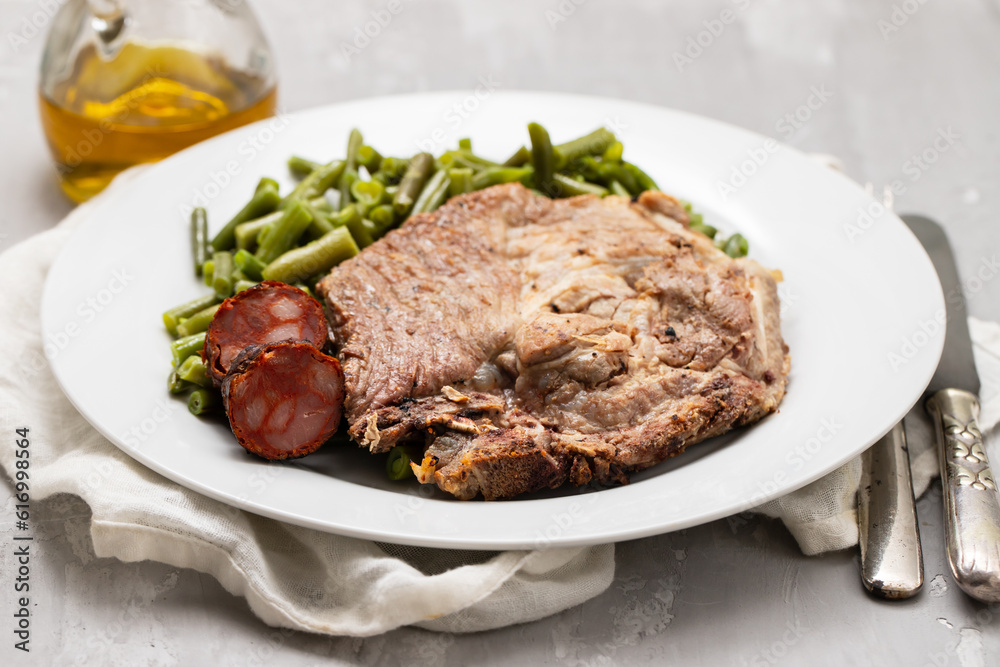 Green beans with meat and smoked sausages on plate