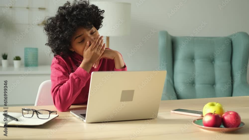 Sleepy african american woman sitting at table with laptop and yawning. Tired overworked girl lazy to work. Student businesswoman relaxing bored in home office after work on laptop computer Sleepy african american woman sitting at table with laptop and yawning. Tired overworked girl lazy to work. Student businesswoman relaxing bored in home office after work on laptop computer