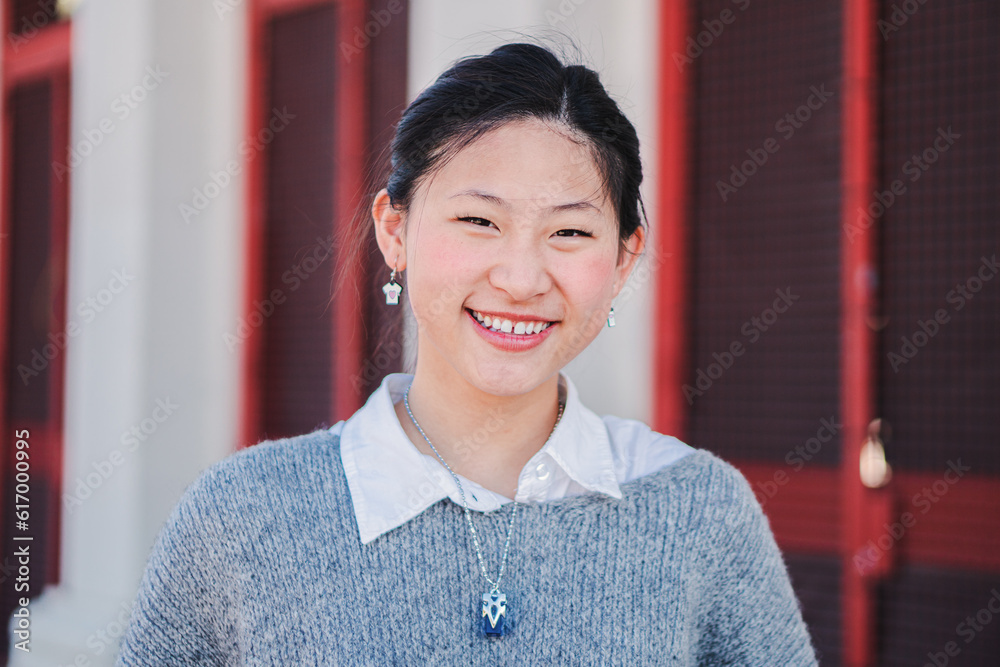 Close up individual portrait of happy chinese young adult woman smiling and looking at camera. One teengage school girl staring front with friendly expression and white teeth. Cheerful female posing