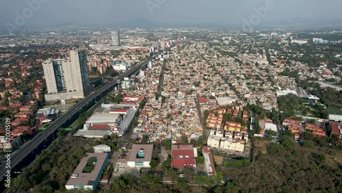 backwards drone shot of Cuicuilco pyramid in Mexico city near poor neighborhoods photo