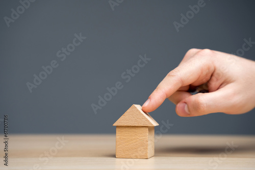 The man points to a miniature house. The concept of real estate and affordable housing. Mortgage rates and loans. Sale, purchase and rent of apartments. Taxes, utilities and insurance photo