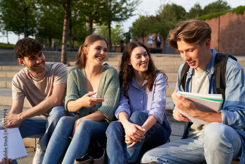 Group of caucasian students sitting outside the university campus
