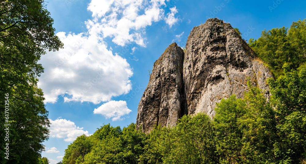 Twin rocks called “Pater und Nonne“ (father and nun) near Iserlohn-Letmathe Sauerland Germany in the lenne valley, natural site. Panoramic view on a sunny summer day with blue sky and green foliage.