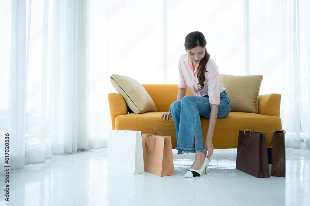 Portrait of young asian woman sitting on sofa in the shop's VIP lounge with shopping bags Portrait of young asian woman sitting on sofa in the shop's VIP lounge with shopping bags