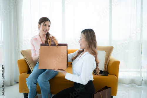 The receptionist delivers the goods that the customer has already purchased to Asian women on the sofa with shopping bags