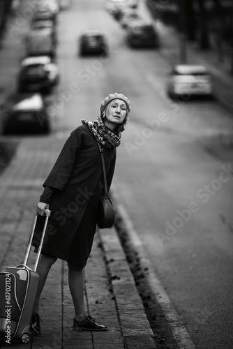 On the side of the road, a woman with a suitcase votes. Black and white photo.