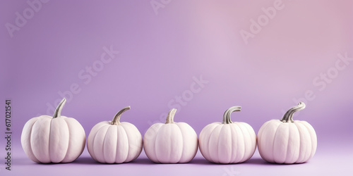 White pumpkins in a row on pastel violet background