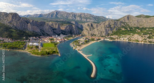 Fototapeta Naklejka Na Ścianę i Meble -  Amazing panoramic view of the picturesque town of Omish in Croatia, the cliffs, the old houses with red roofs, the historic buildings and the river flowing into the turquoise Adriatic Sea