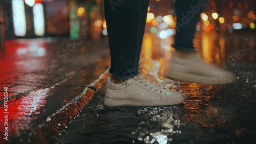 Close-up of a woman's feet stepping into a muddy puddle and making a splash