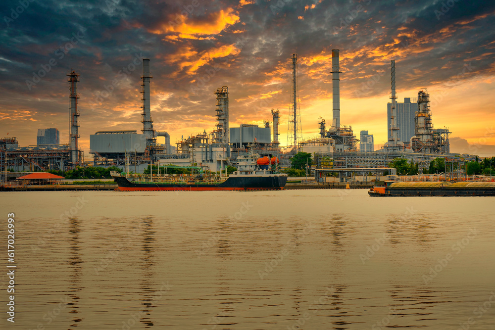 An oil refinery located on the Chao Phraya River, in Bangkok, Thailand, is a large industrial factory. and the golden evening sky has Big clouds when it's about to rain