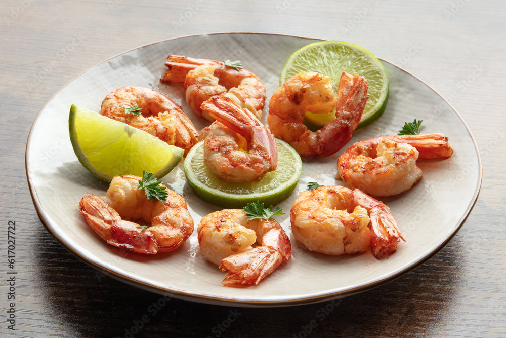 Shrimps. Cooked shrimp with lime on a white plate, on a rustic table. Spicy gourmet meal