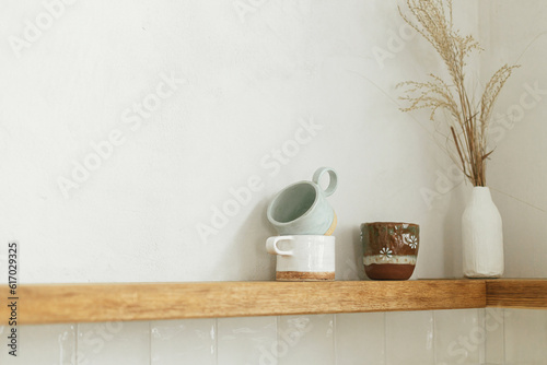 Wooden shelf with utensils  cups and decor on rustic wall background in modern kitchen in new scandinavian house. Modern kitchen interior and stylish accessories